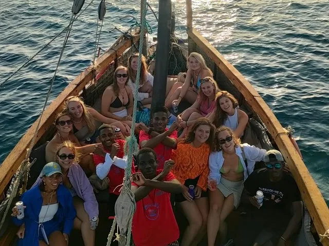 Un grupo de personas relajándose y sonriendo juntas en un barco de madera.
