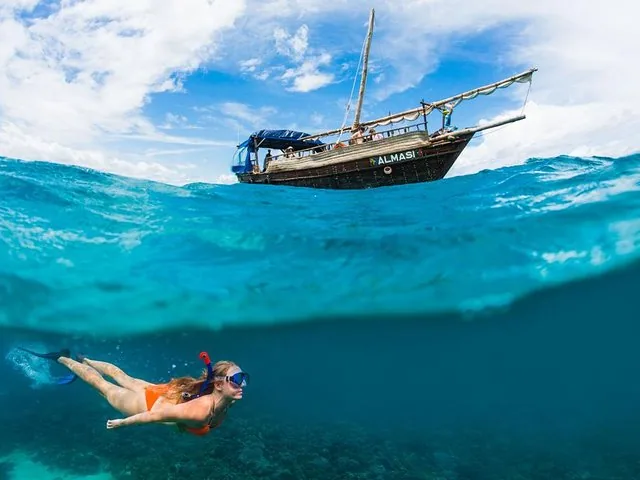 Vista subacuática dividida que muestra a una persona haciendo esnórquel abajo y un barco arriba.
